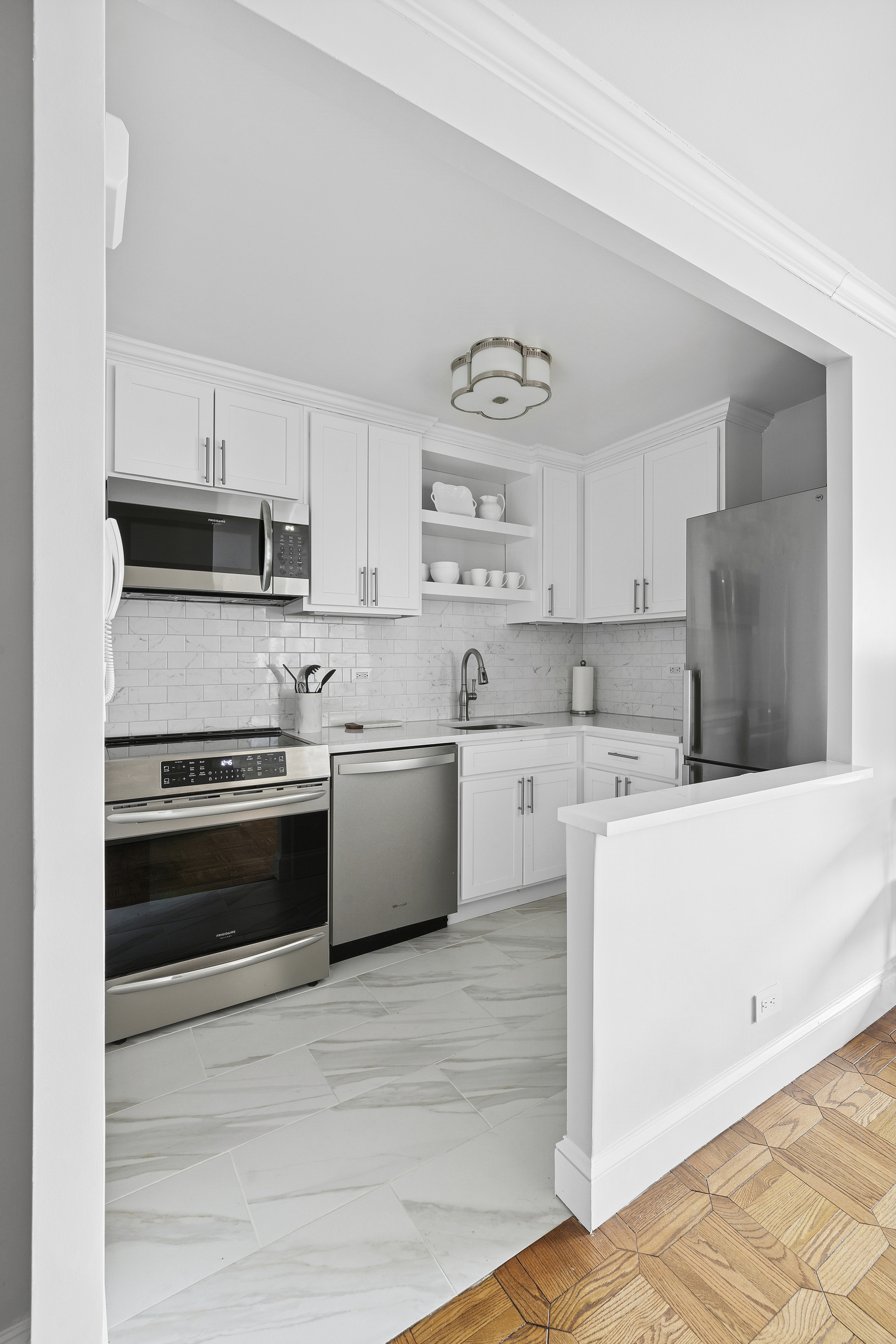 1065 Park Avenue, Unit 27C Manhattan, NY 10128 - Photo 5 of 10 a kitchen with stainless steel appliances and white cabinets