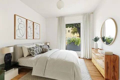 a bedroom with a bed a mirror on the dresser and a large window