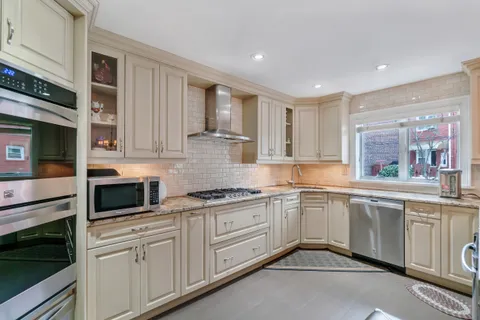 a kitchen with white cabinets stainless steel appliances and a window