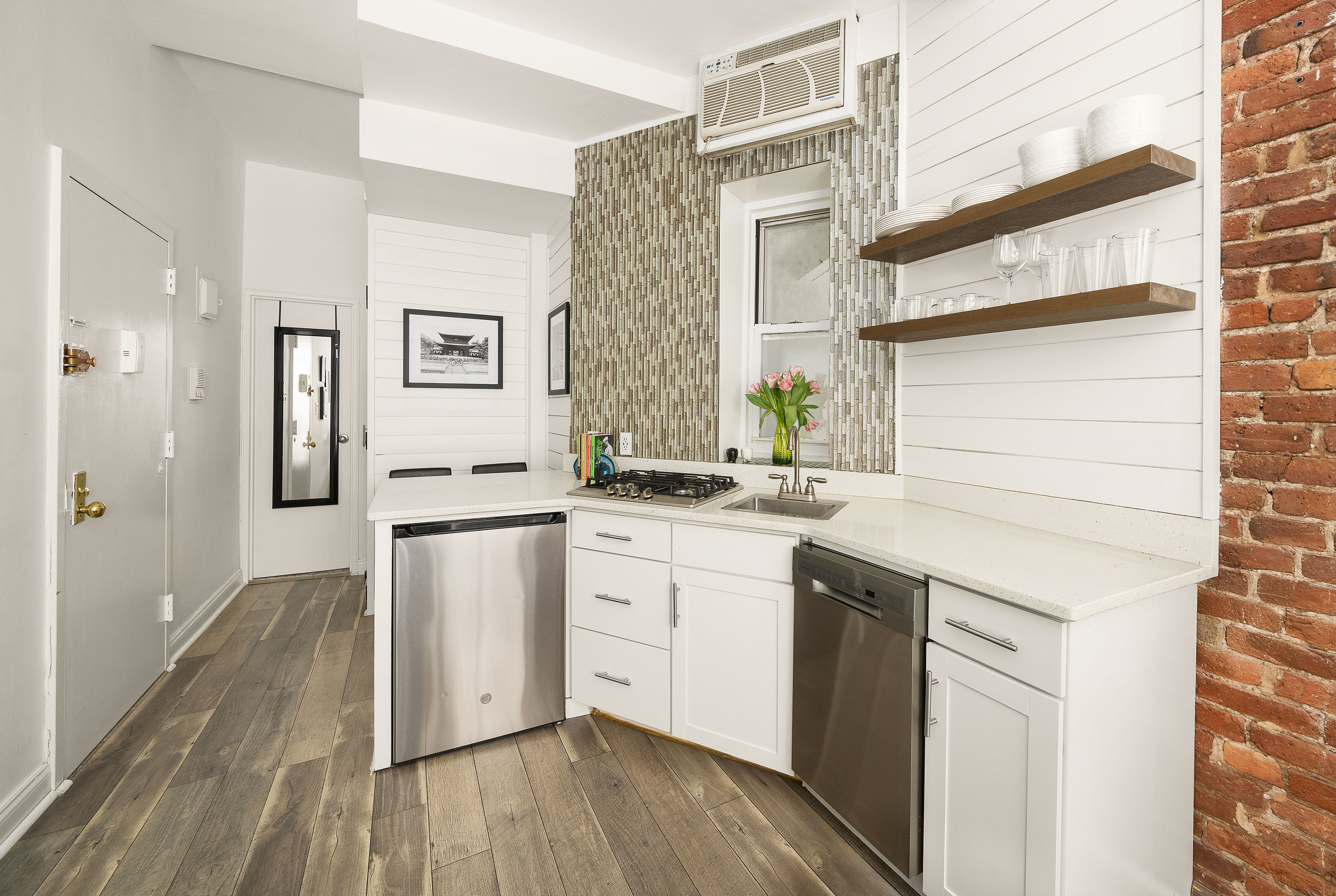77 Perry Street, Unit 1A Manhattan, NY 10014 - Photo 4 of 6 a kitchen with a sink cabinets stainless steel appliances and a window
