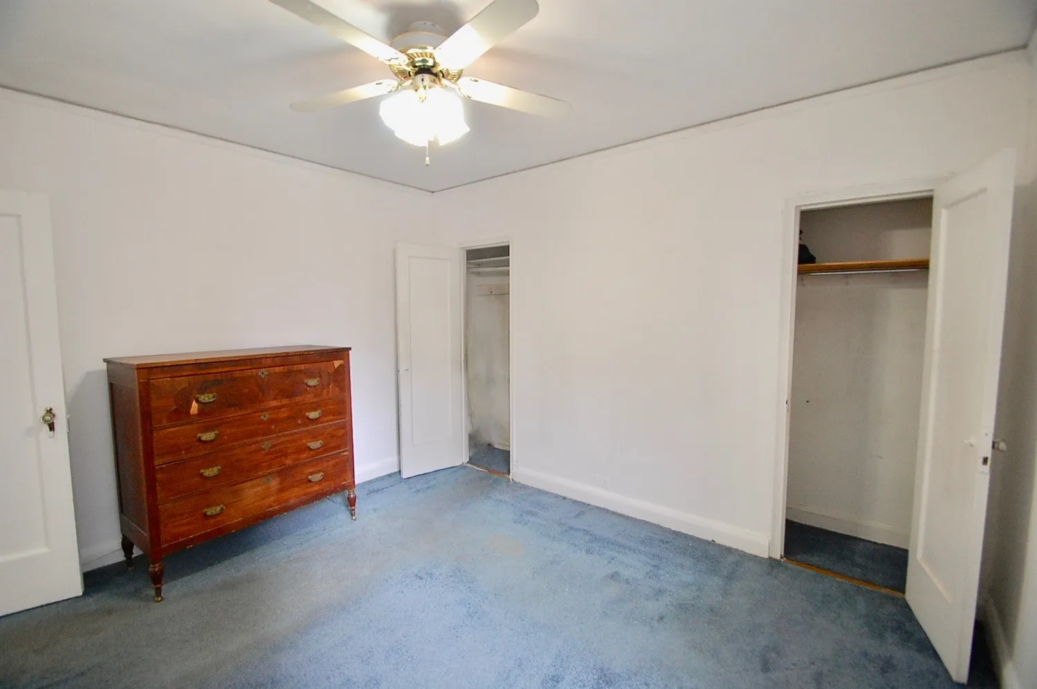 an empty room with closet and a ceiling fan