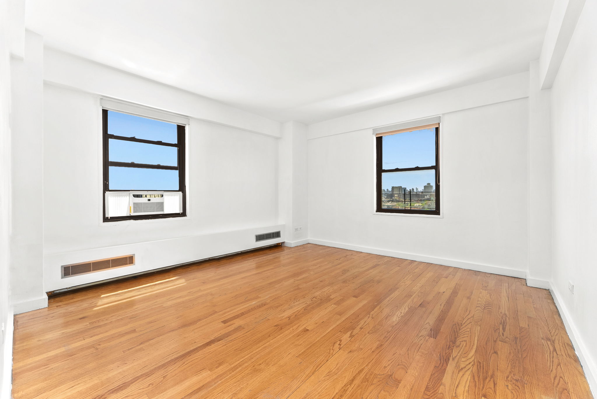 345 West 145th Street, Unit 8C3 Manhattan, NY 10031 - Photo 8 of 12 an empty room with wooden floor and windows