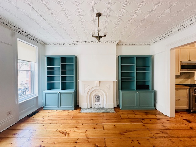 a view of an empty room with a window and kitchen view