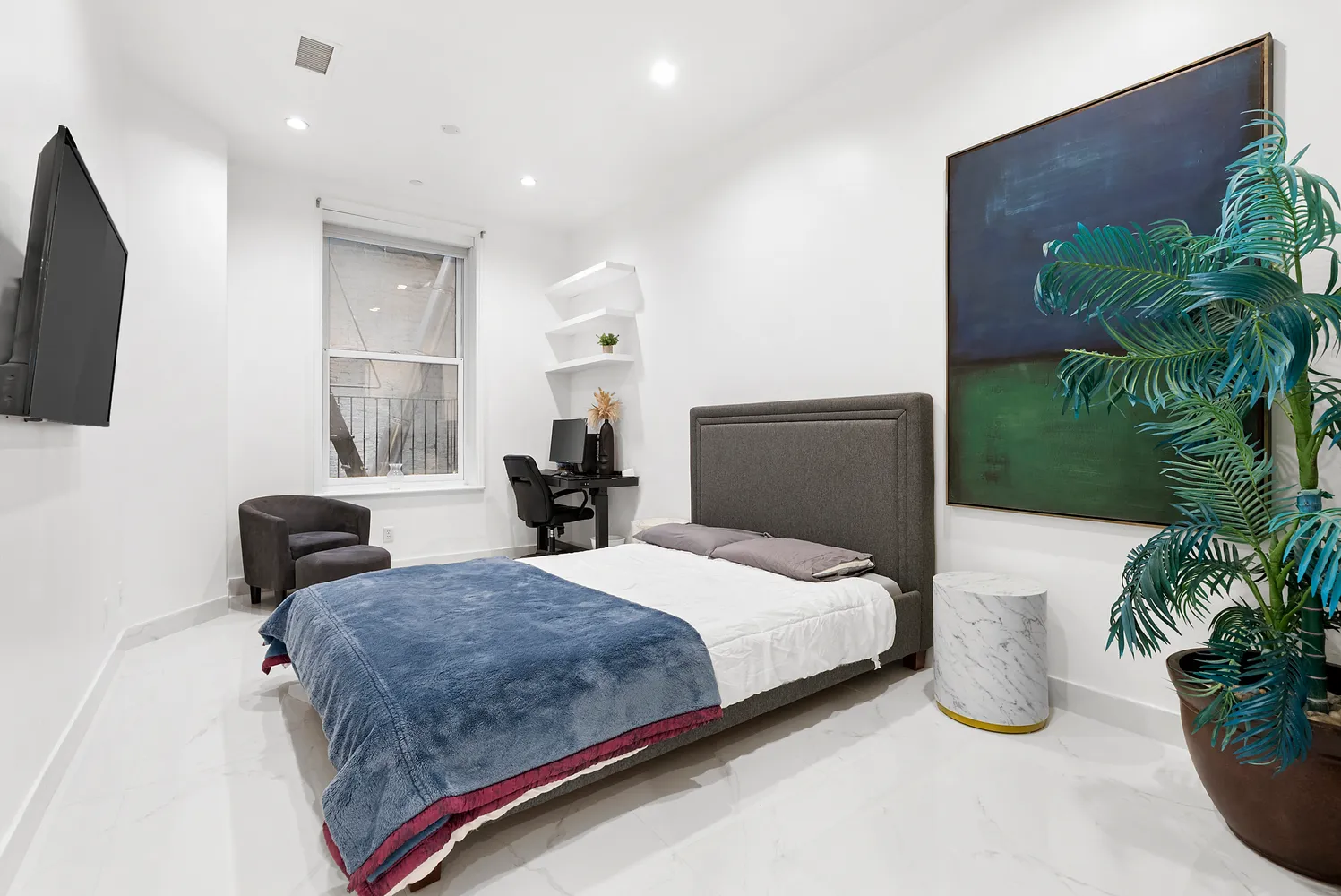 a bedroom with a large bed and a potted plant