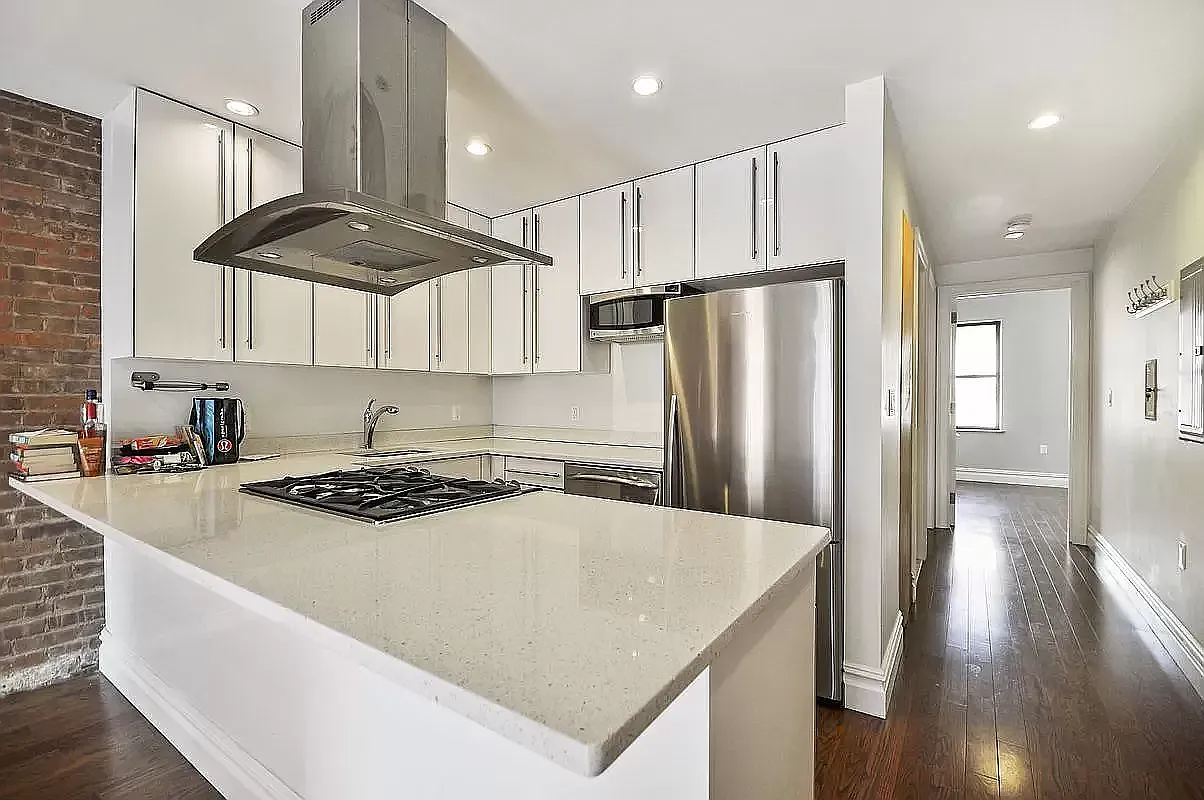 1569 2nd Avenue, Unit 301 Manhattan, NY 10028 - Photo 3 of 9 a kitchen with stainless steel appliances granite countertop a sink a stove a refrigerator and island