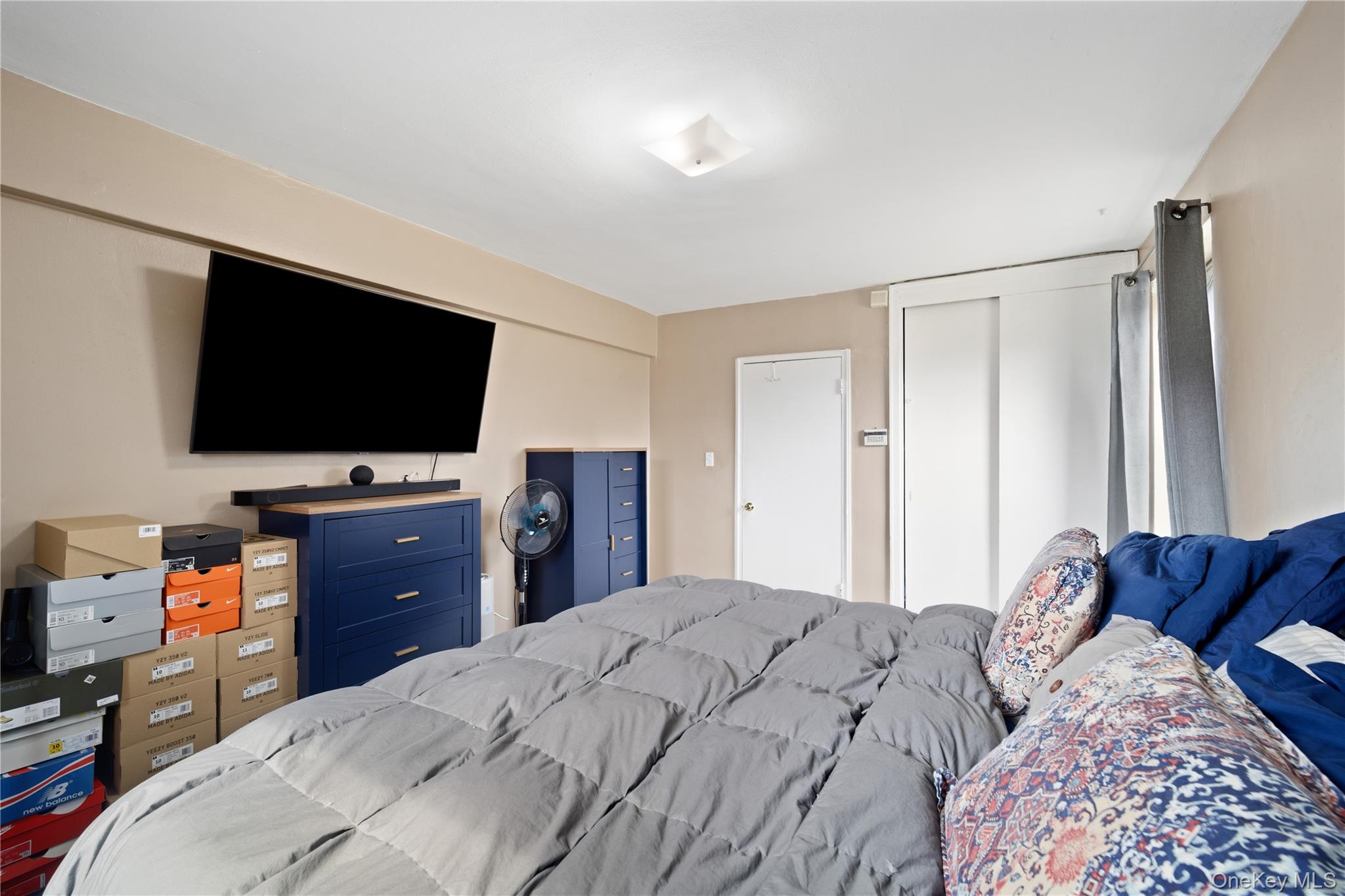 73-11 Bell Boulevard, Unit 2C Queens, NY 11364 - Photo 4 of 16 a bedroom with a bed and a flat screen tv