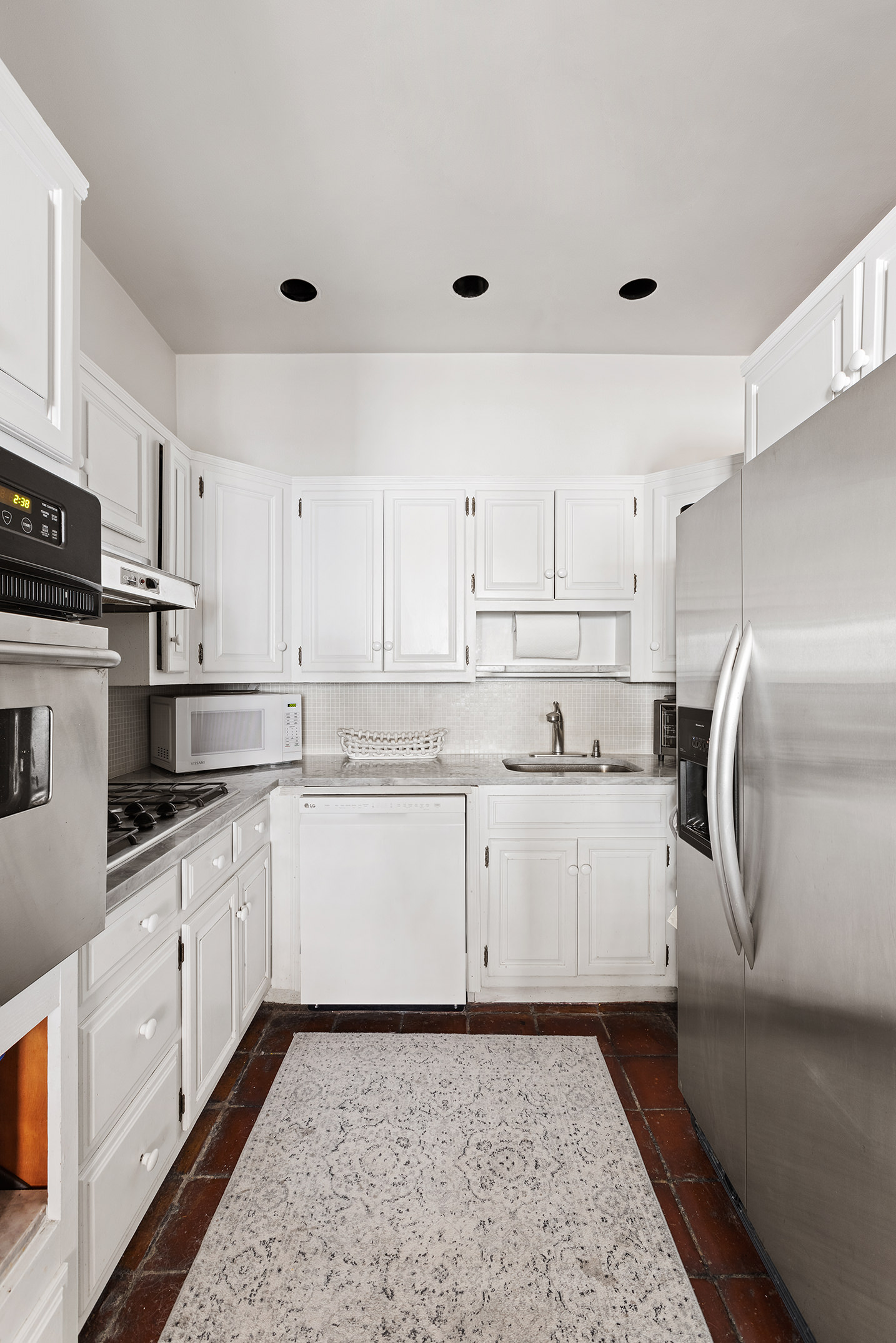 138 West 73rd Street Manhattan, NY 10023 - Photo 10 of 35 a kitchen with granite countertop white cabinets and white appliances