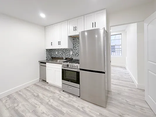 55 Spring Street, Unit 7 Manhattan, NY 10012 - Photo 3 of 12 a kitchen with a refrigerator stove and white cabinets