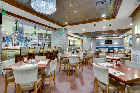 a room with lots of tables a large window and chairs