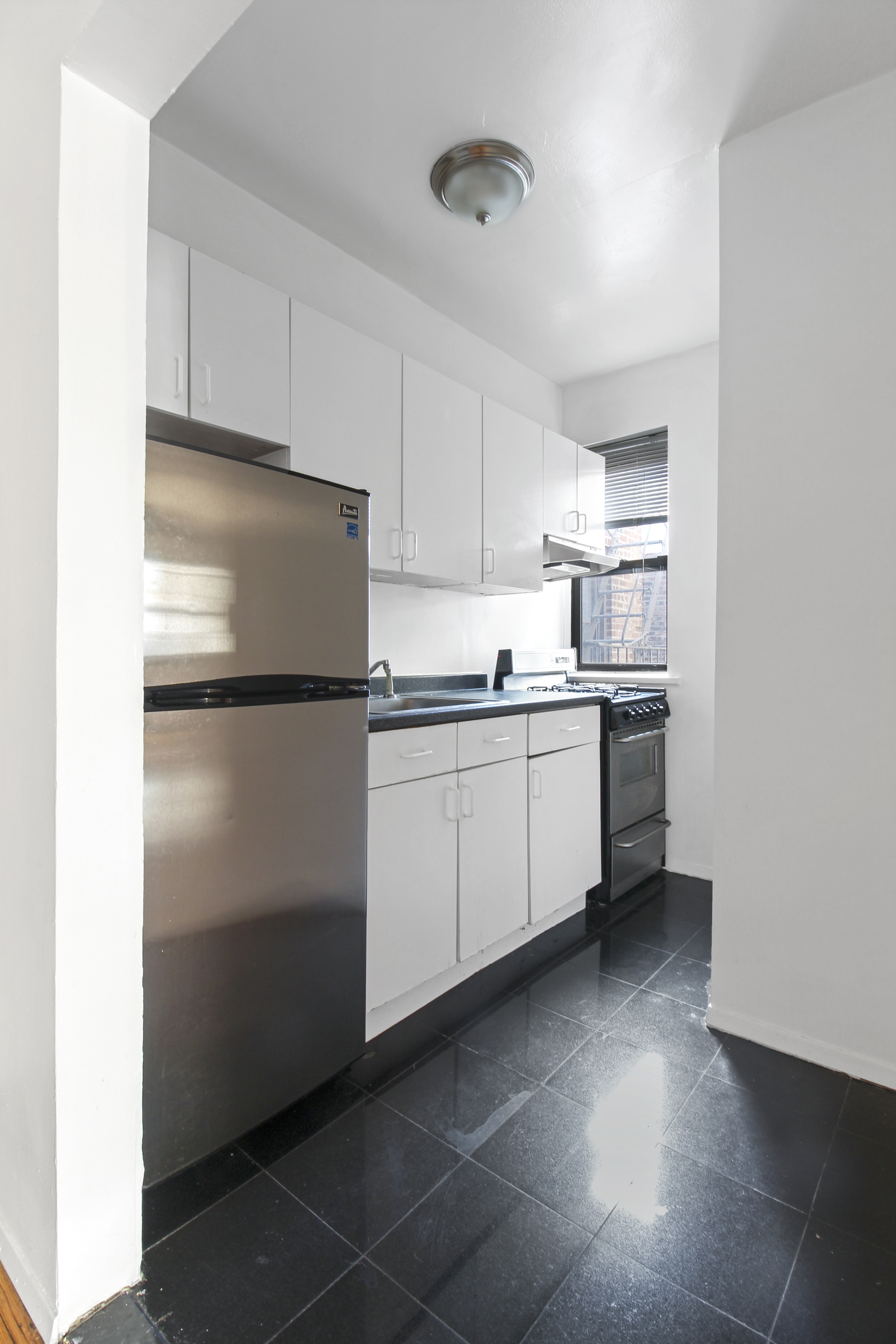 315 East 56th Street, Unit 6C Manhattan, NY 10022 - Photo 2 of 5 a kitchen with a refrigerator and white cabinets