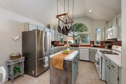 a kitchen with stainless steel appliances granite countertop a refrigerator a sink dishwasher a stove and a dining table with wooden floor