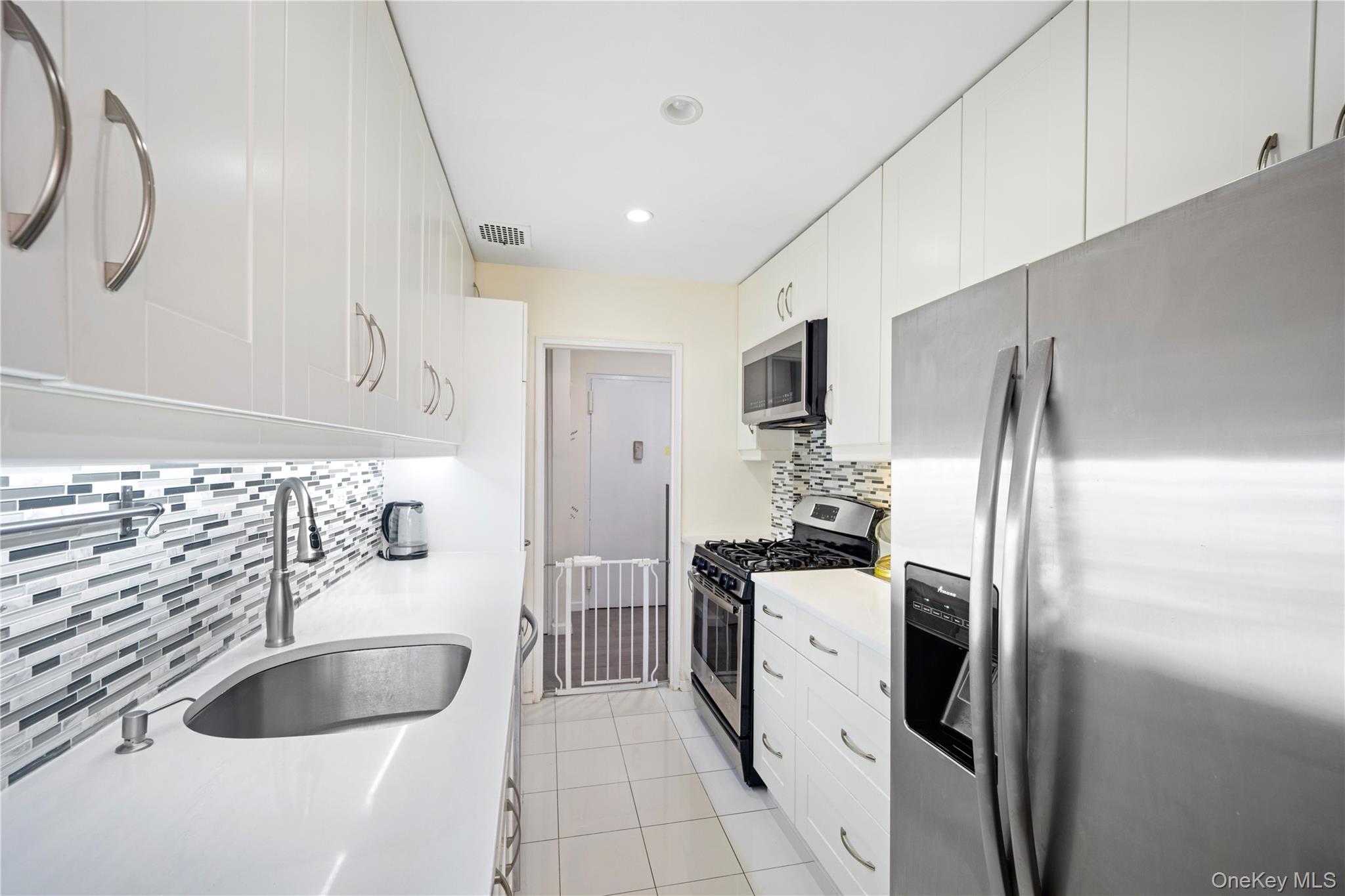 75-34 Bell Boulevard, Unit LD Queens, NY 11364 - Photo 6 of 26 a kitchen with stainless steel appliances granite countertop a sink stove and refrigerator