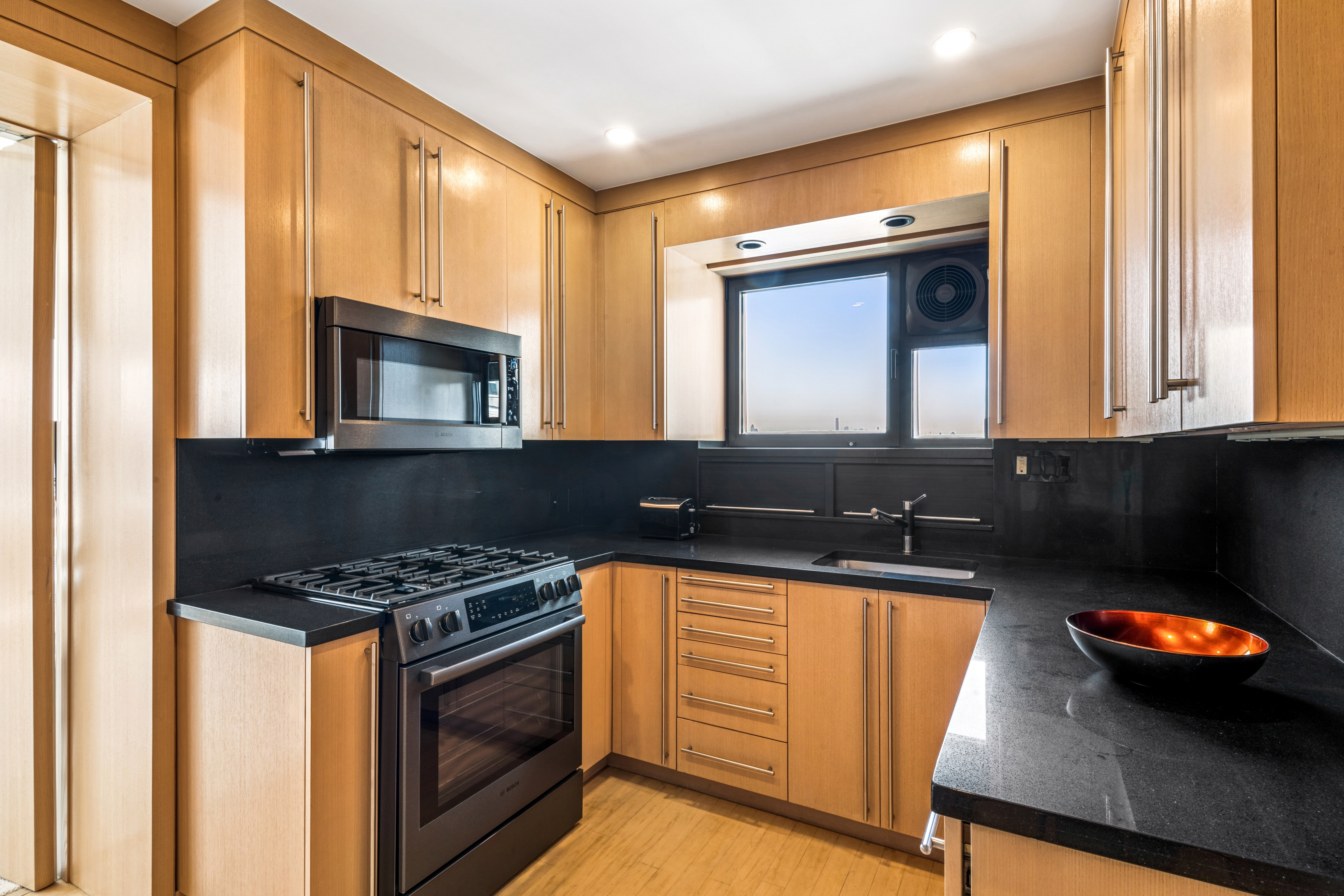 45 Sutton Place South, Unit 10F Manhattan, NY 10022 - Photo 6 of 15 a kitchen with granite countertop a stove a sink and a microwave