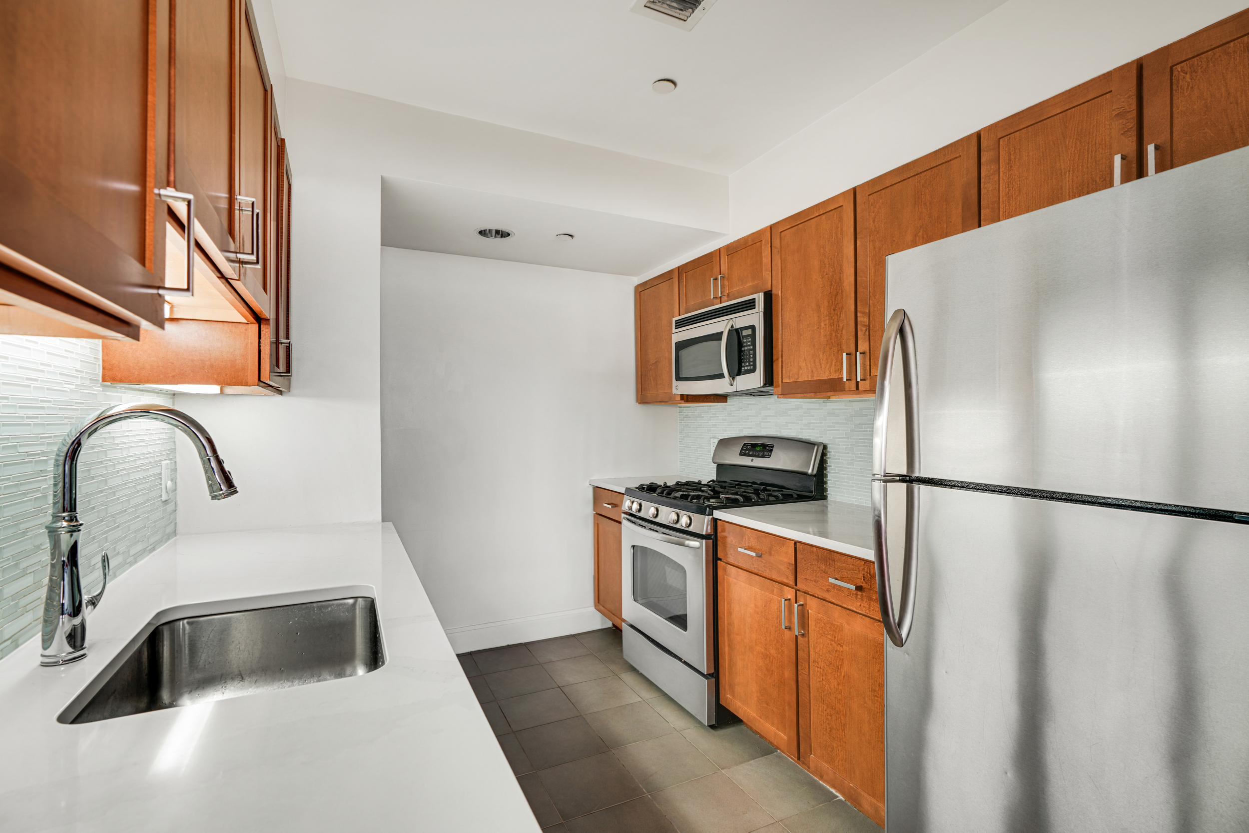 1820 Madison Avenue, Unit 7C Manhattan, NY 10035 - Photo 4 of 17 a kitchen with stainless steel appliances a refrigerator sink and white cabinets