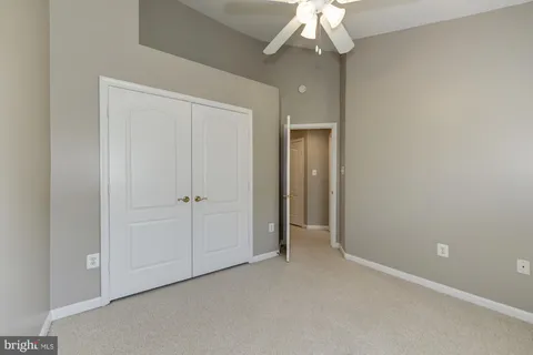 an empty room with a chandelier fan and closet