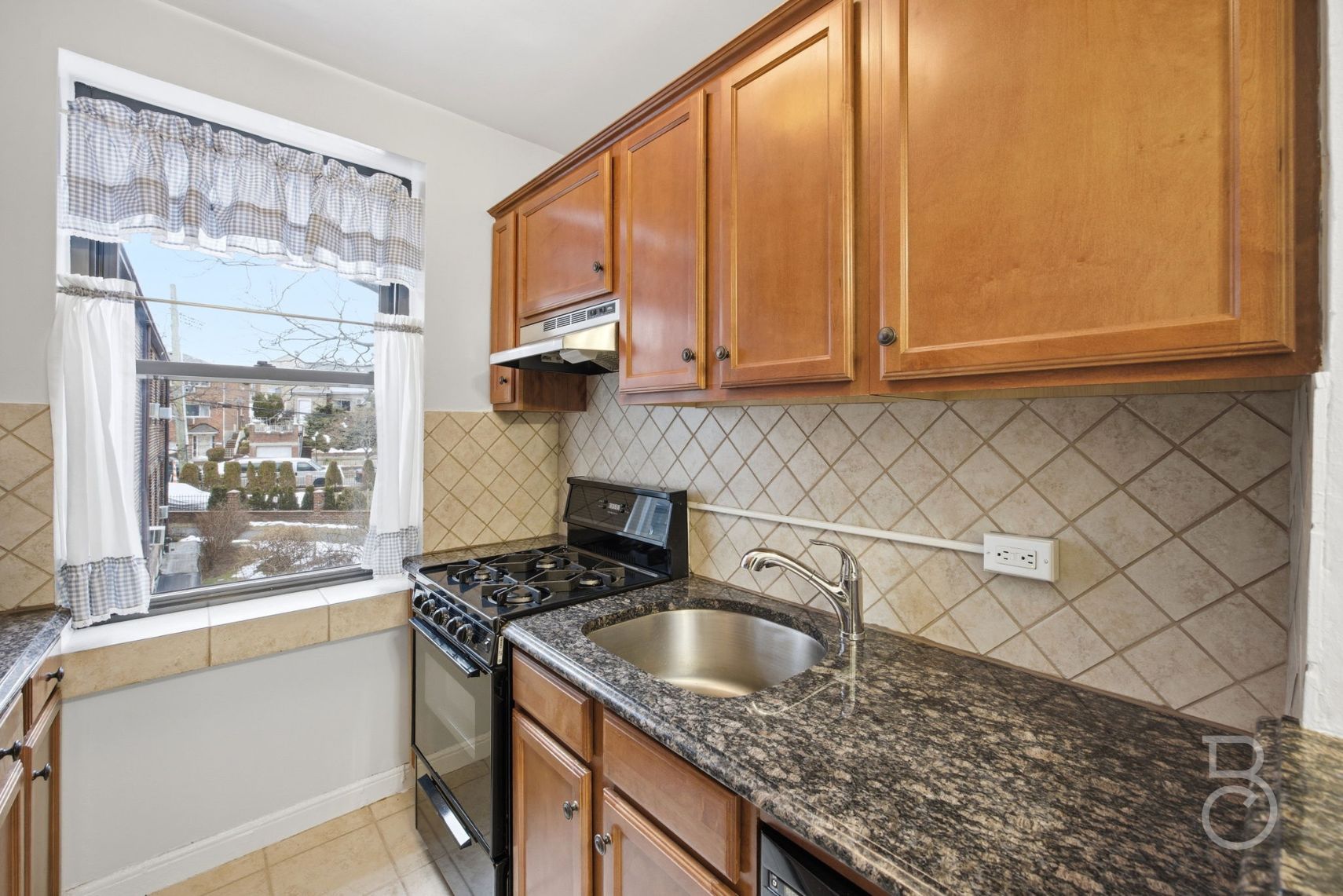 78-15 19th Drive, Unit B2 Queens, NY 11370 - Photo 6 of 17 a kitchen with granite countertop a sink a stove and cabinets