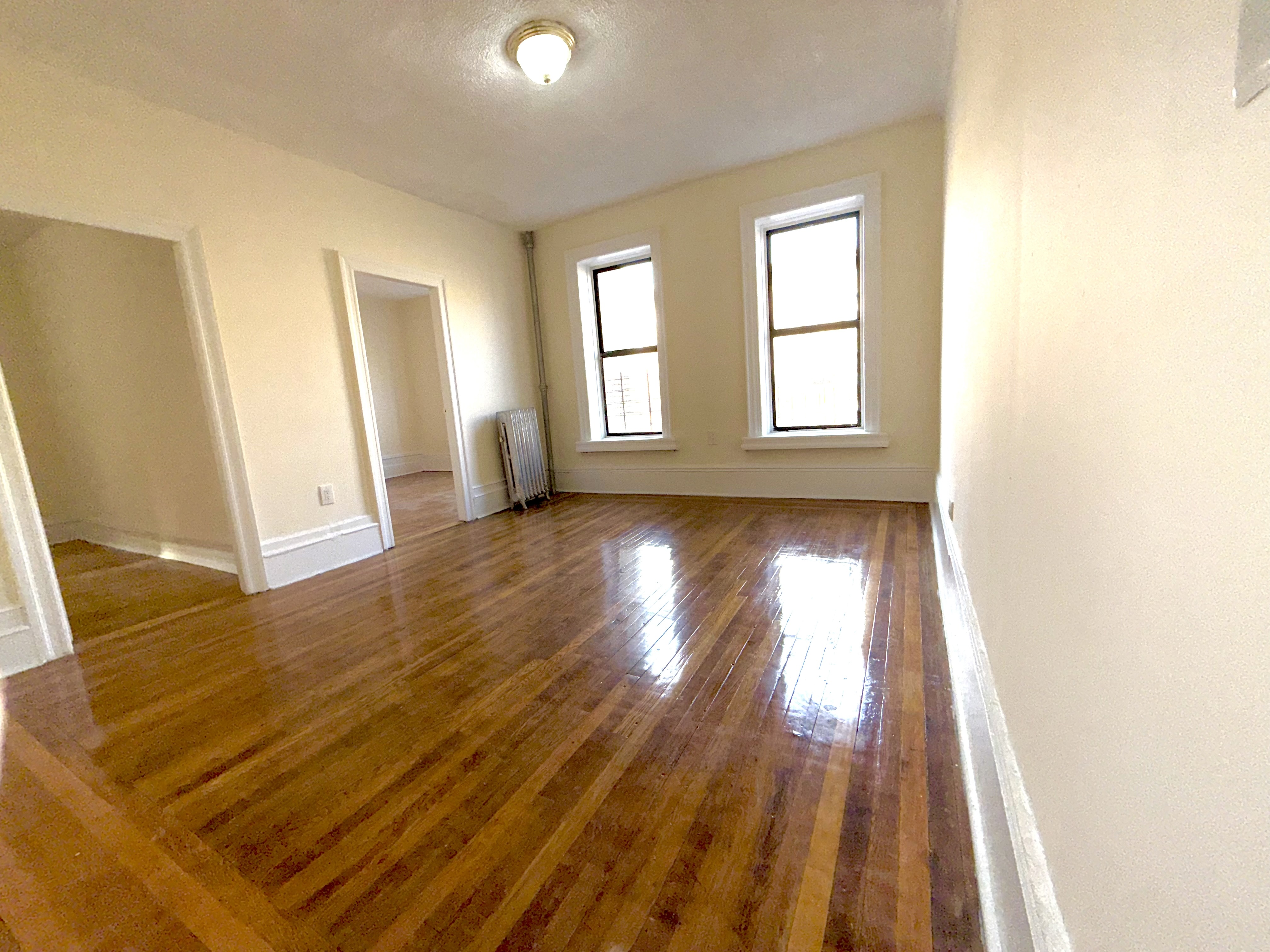 153 Vermilyea Avenue, Unit 4B Manhattan, NY 10034 - Photo 2 of 9 a view of an empty room with wooden floor and a window