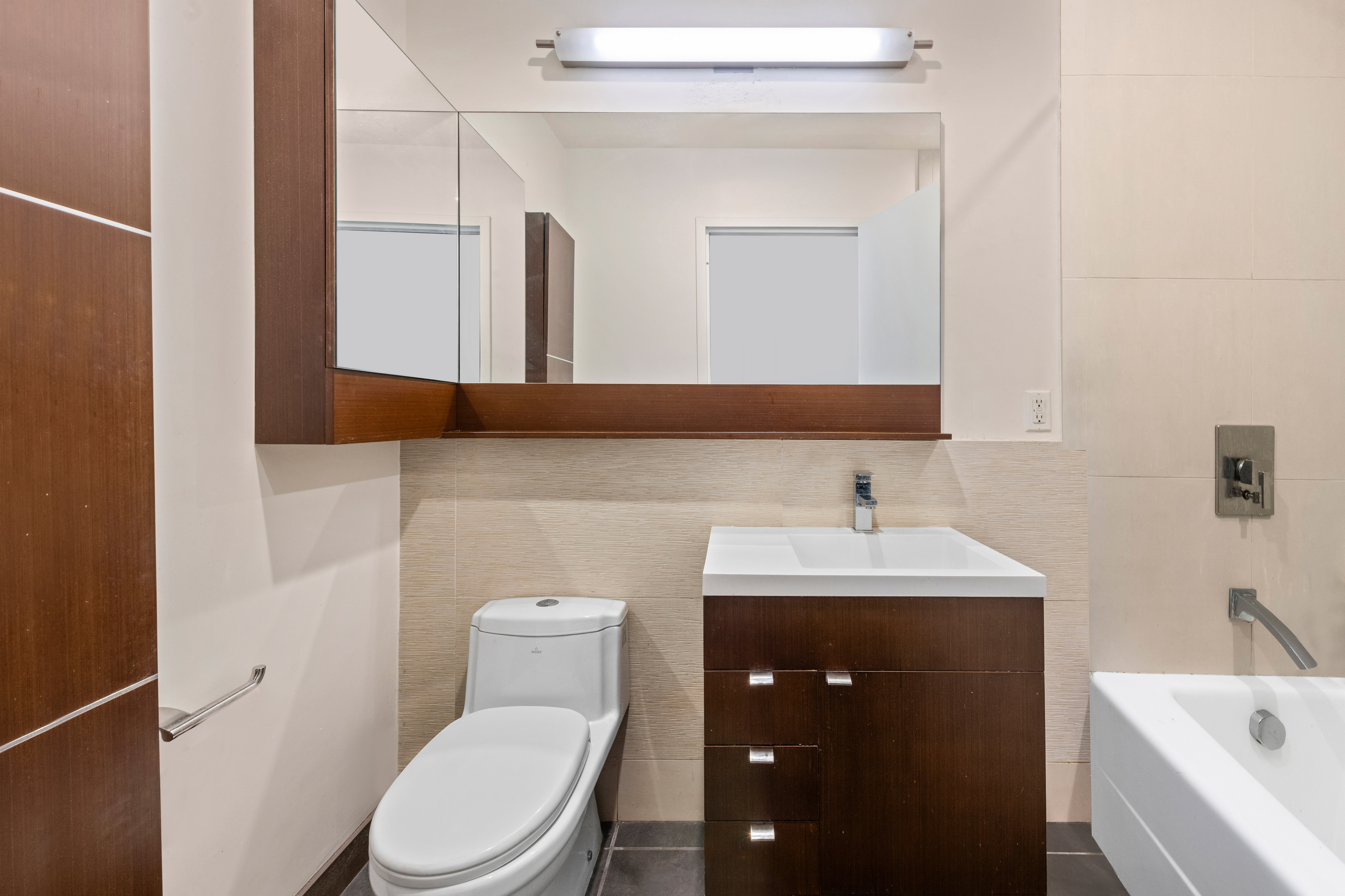 148 East 24th Street, Unit 12B Manhattan, NY 10010 - Photo 4 of 13 a bathroom with a toilet a sink a tub and mirror
