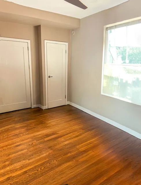 a view of an empty room with wooden floor and a window