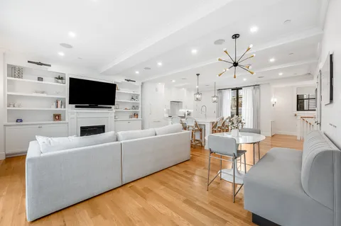 a living room with furniture a flat screen tv and kitchen view