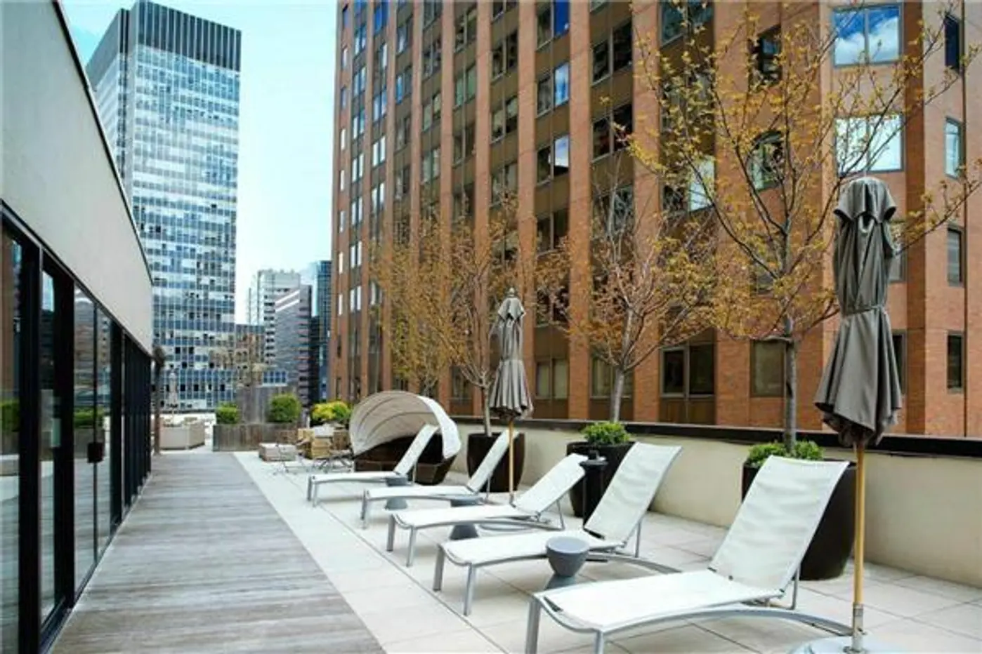 1 Wall Street Court, Unit 506 Manhattan, NY 10005 - Photo 5 of 8 a view of a patio with couches table and chairs with wooden floor and fence