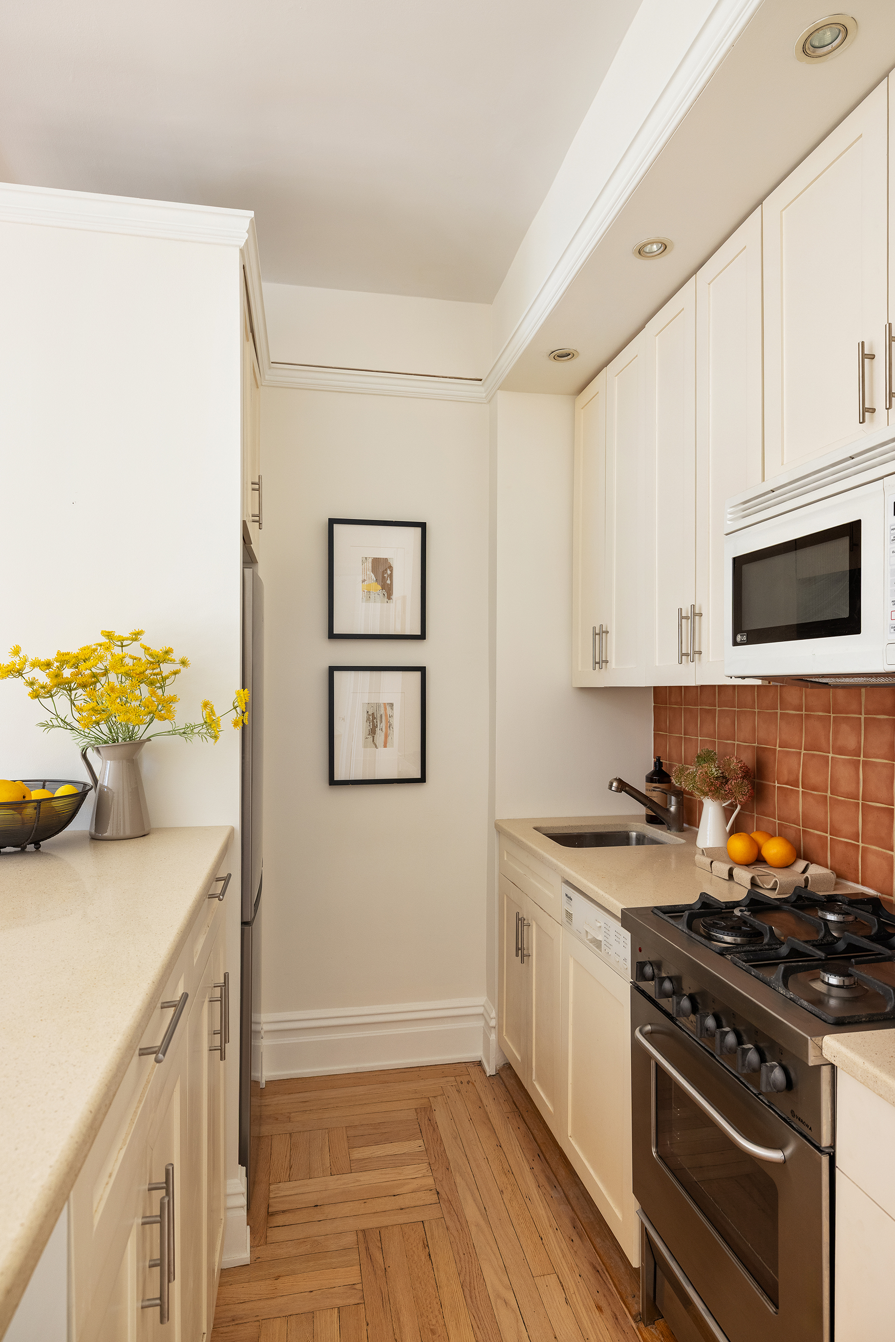 30 5th Avenue, Unit 6H Manhattan, NY 10011 - Photo 8 of 17 a kitchen with stainless steel appliances a stove a microwave a sink and cabinets