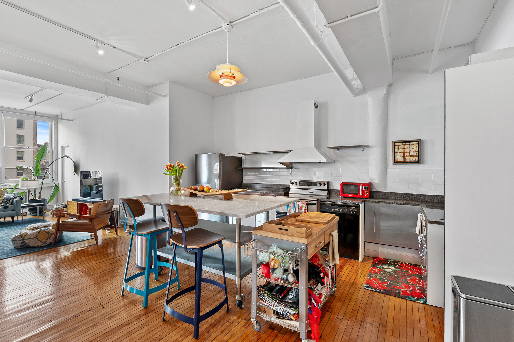 565 Broadway, Unit 8W Manhattan, NY 10012 - Photo 6 of 23 a open kitchen with stainless steel appliances granite countertop a stove a refrigerator a dining table and chairs with wooden floor