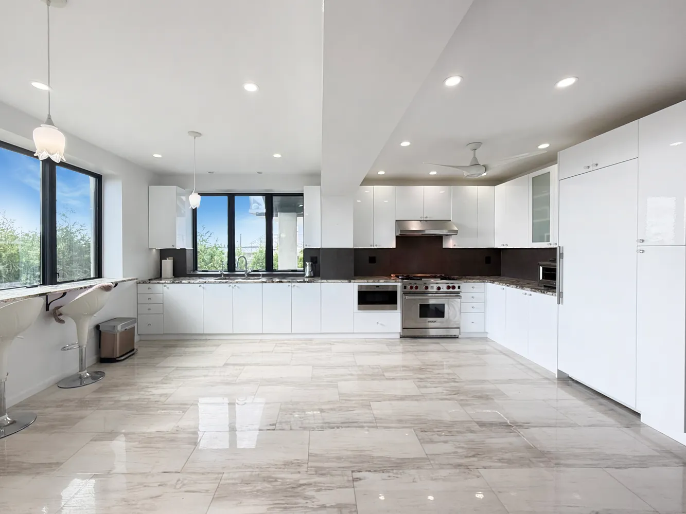 a view of kitchen with stainless steel appliances kitchen island granite countertop a stove a sink a refrigerator and white cabinets with wooden floor