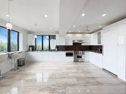 a view of kitchen with stainless steel appliances kitchen island granite countertop a stove a sink a refrigerator and white cabinets with wooden floor