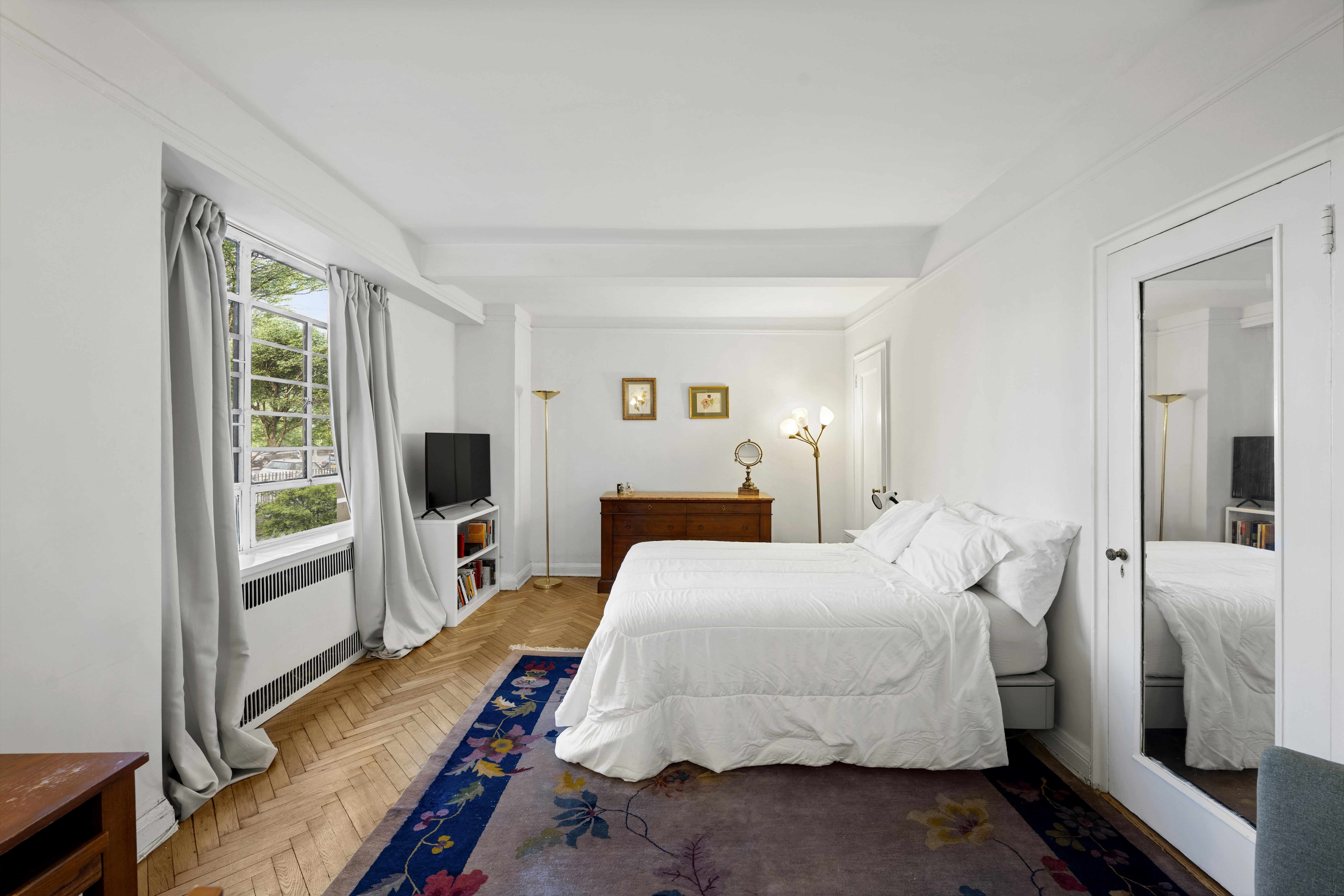 140 Riverside Drive, Unit 1G Manhattan, NY 10024 - Photo 7 of 16 a bedroom with a bed and a flat tv screen on dresser