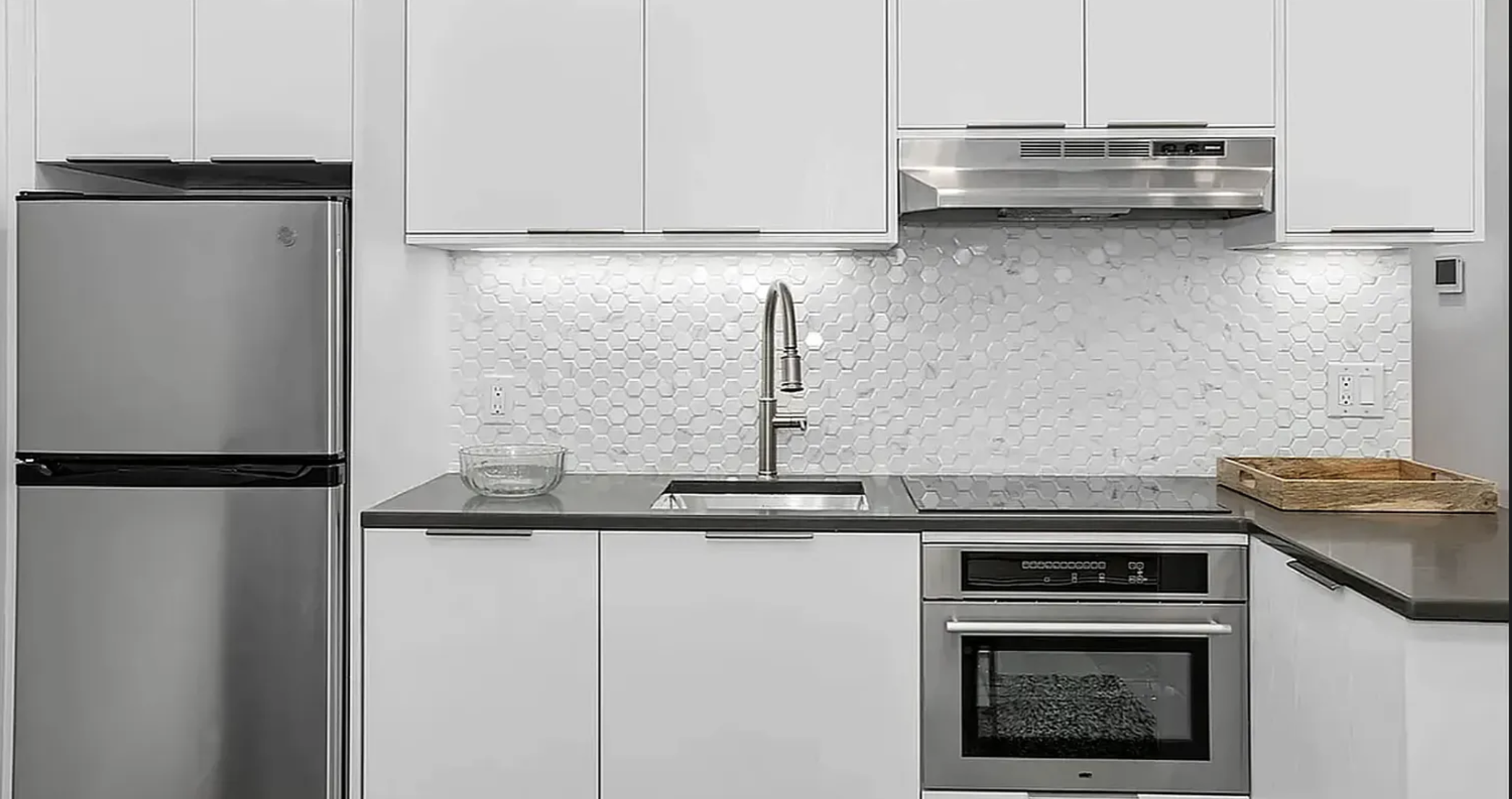 319 Broadway, Unit PHA Brooklyn, NY 11211 - Photo 2 of 6 a kitchen with stainless steel appliances granite countertop a refrigerator a stove and a sink with wooden floor