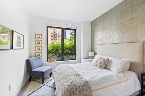 a bedroom with a bed chair and a large window
