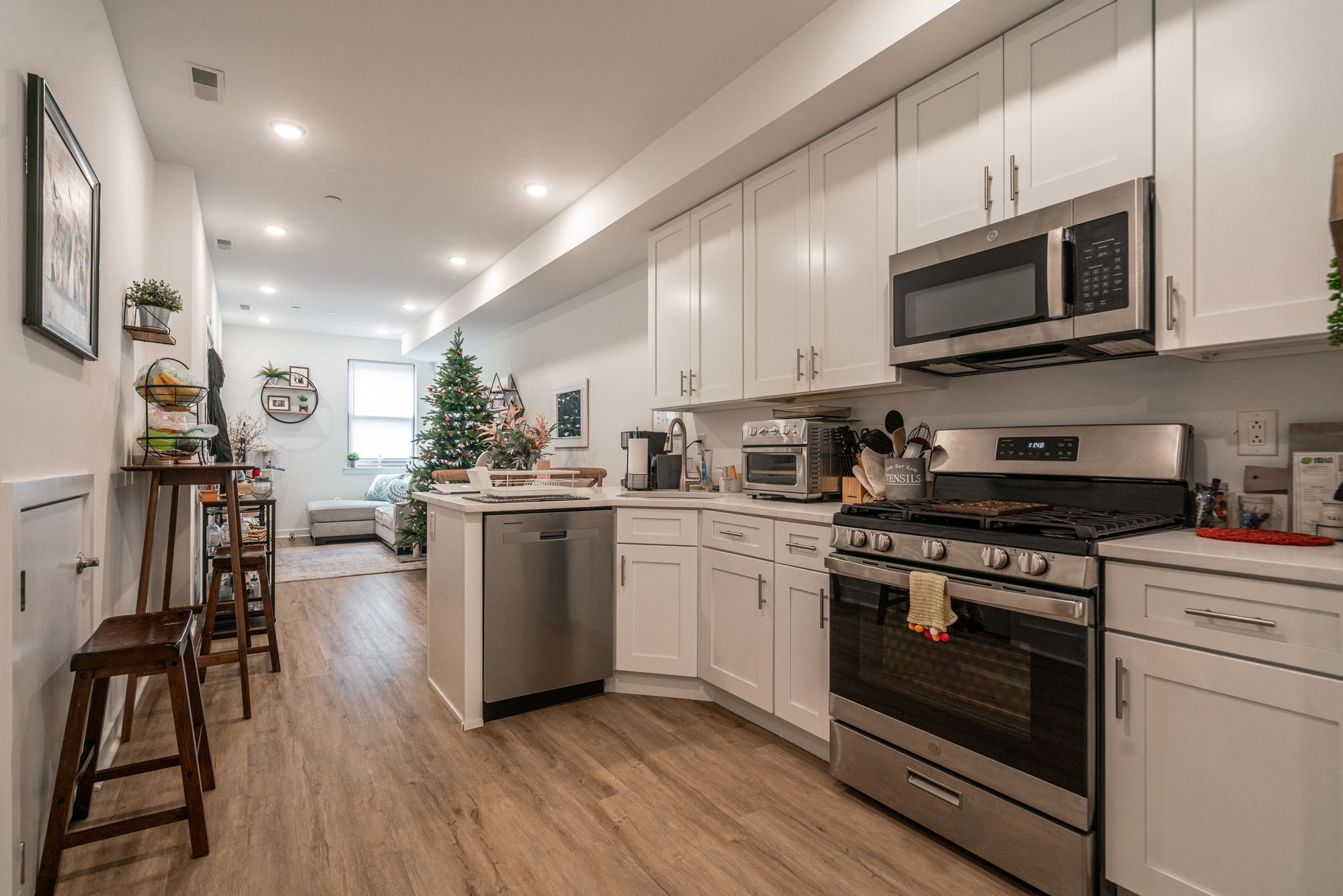 a kitchen with stainless steel appliances granite countertop a stove a microwave a sink a refrigerator white cabinets and wooden floor