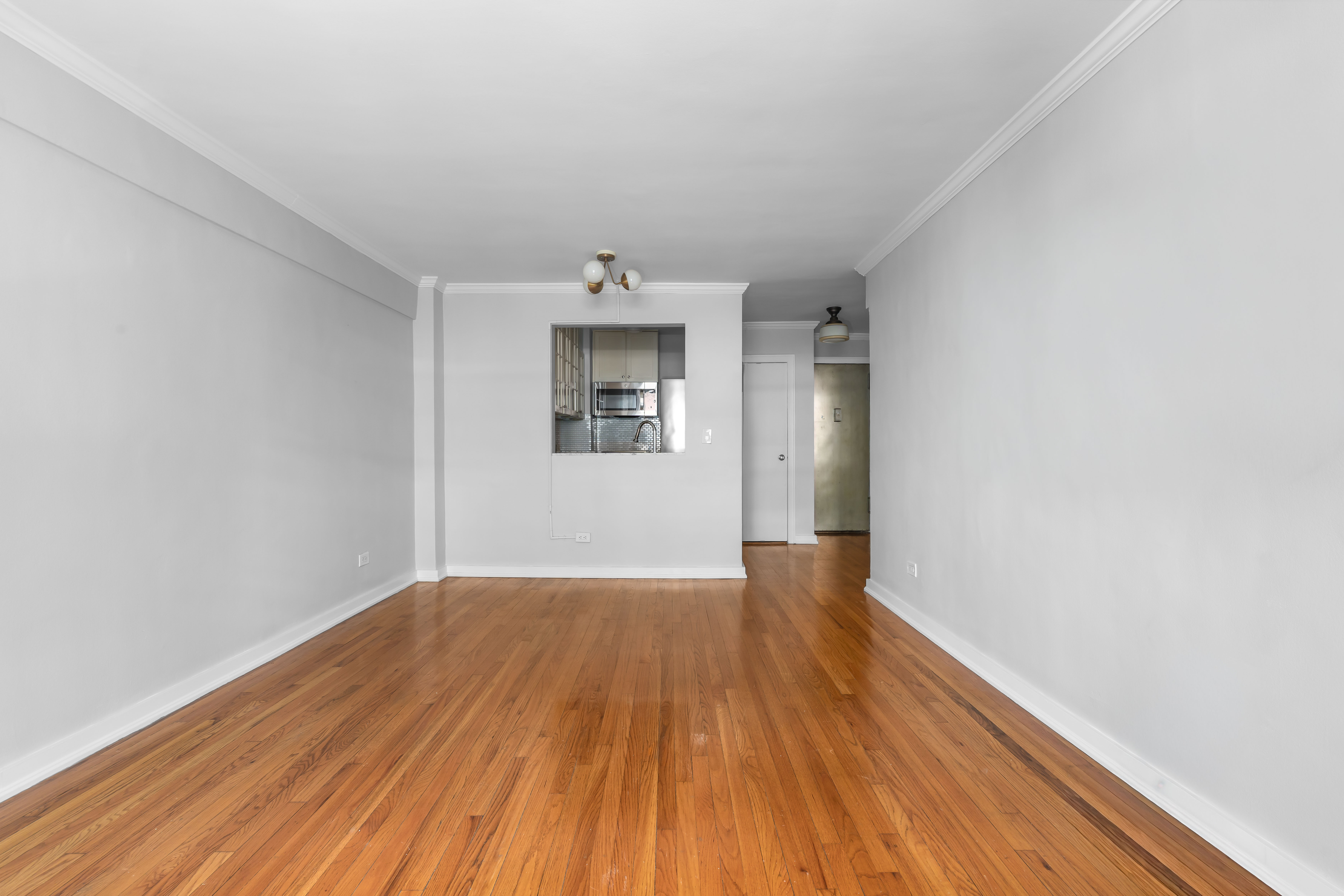 88 Bleecker Street, Unit 2M Manhattan, NY 10012 - Photo 5 of 14 an empty room with wooden floor and windows