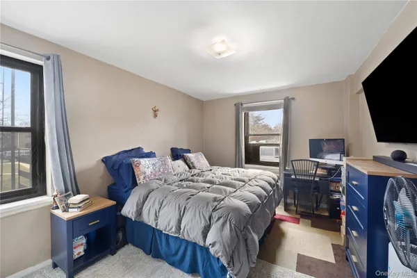 a bedroom with a bed and a flat tv screen on the dresser