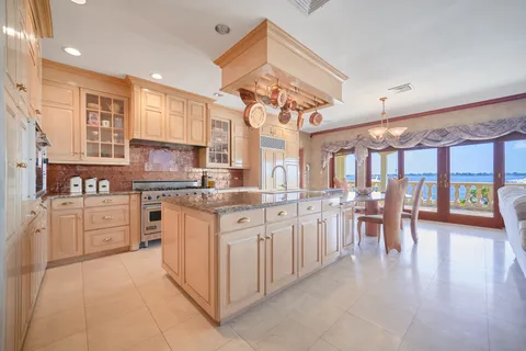 a kitchen with stainless steel appliances granite countertop lots of white cabinets a stove a sink a dining table and chairs