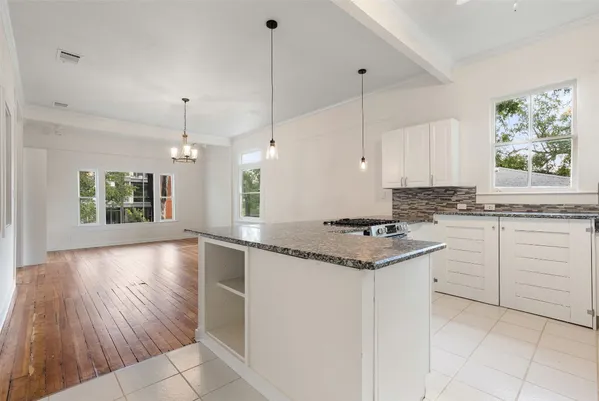 a kitchen with granite countertop a stove a sink and white cabinets with wooden floor