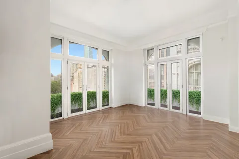 a view of an empty room with wooden floor and windows