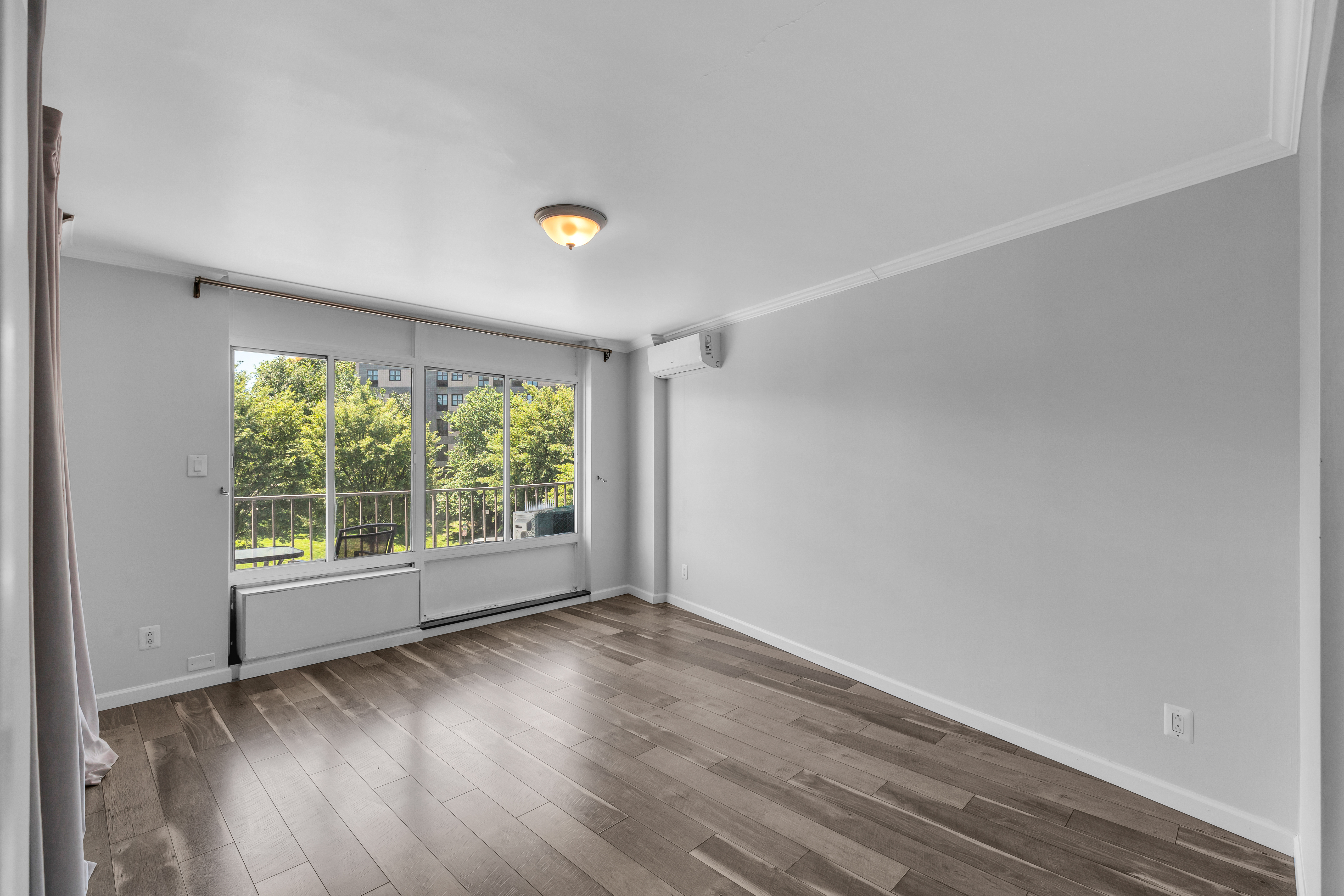 25-40 Shore Boulevard, Unit 2F Queens, NY 11102 - Photo 11 of 31 an empty room with wooden floor and windows