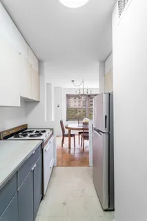 a kitchen with kitchen island a stove a refrigerator a dining table and chairs with wooden floor