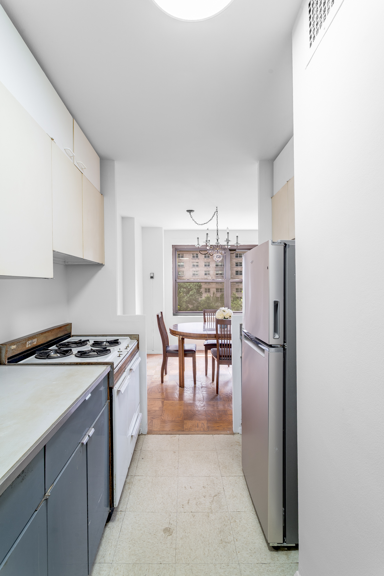 180 West End Avenue, Unit 5H Manhattan, NY 10023 - Photo 8 of 18 a kitchen with kitchen island a stove a refrigerator a dining table and chairs with wooden floor