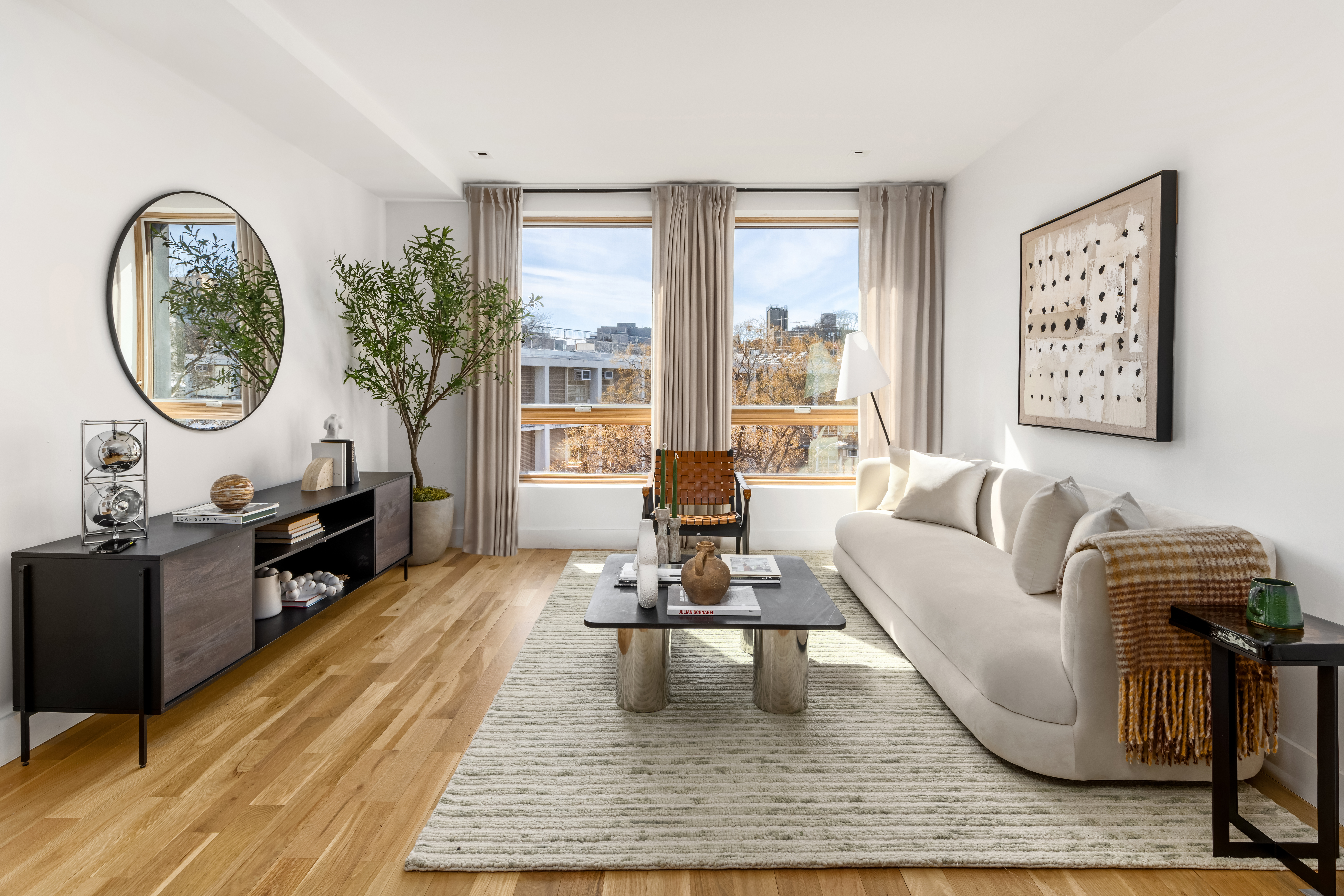 a living room with furniture a large window wooden floor and a rug