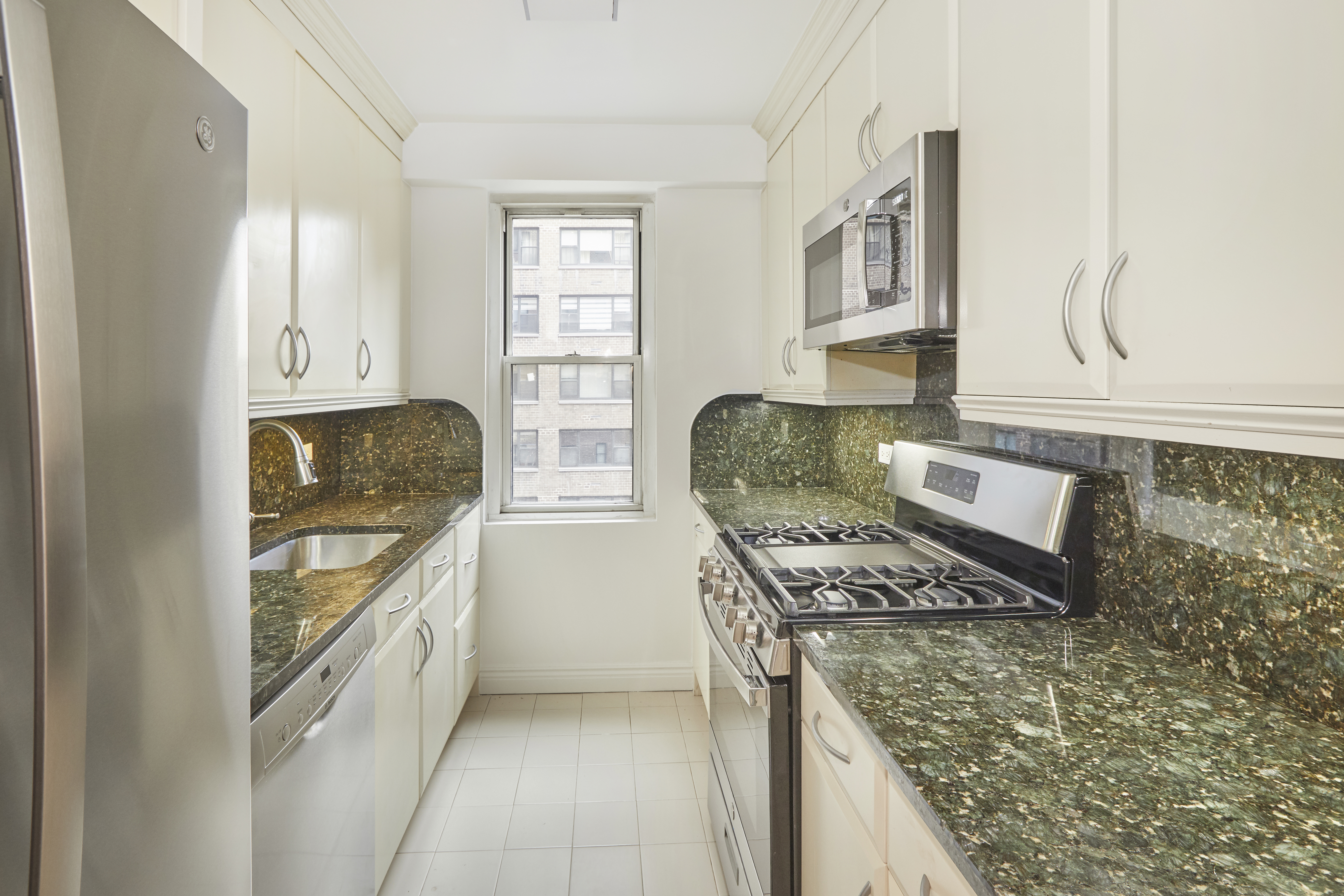 340 East 64th Street, Unit 5B Manhattan, NY 10065 - Photo 9 of 19 a kitchen with stainless steel appliances granite countertop a stove and a refrigerator