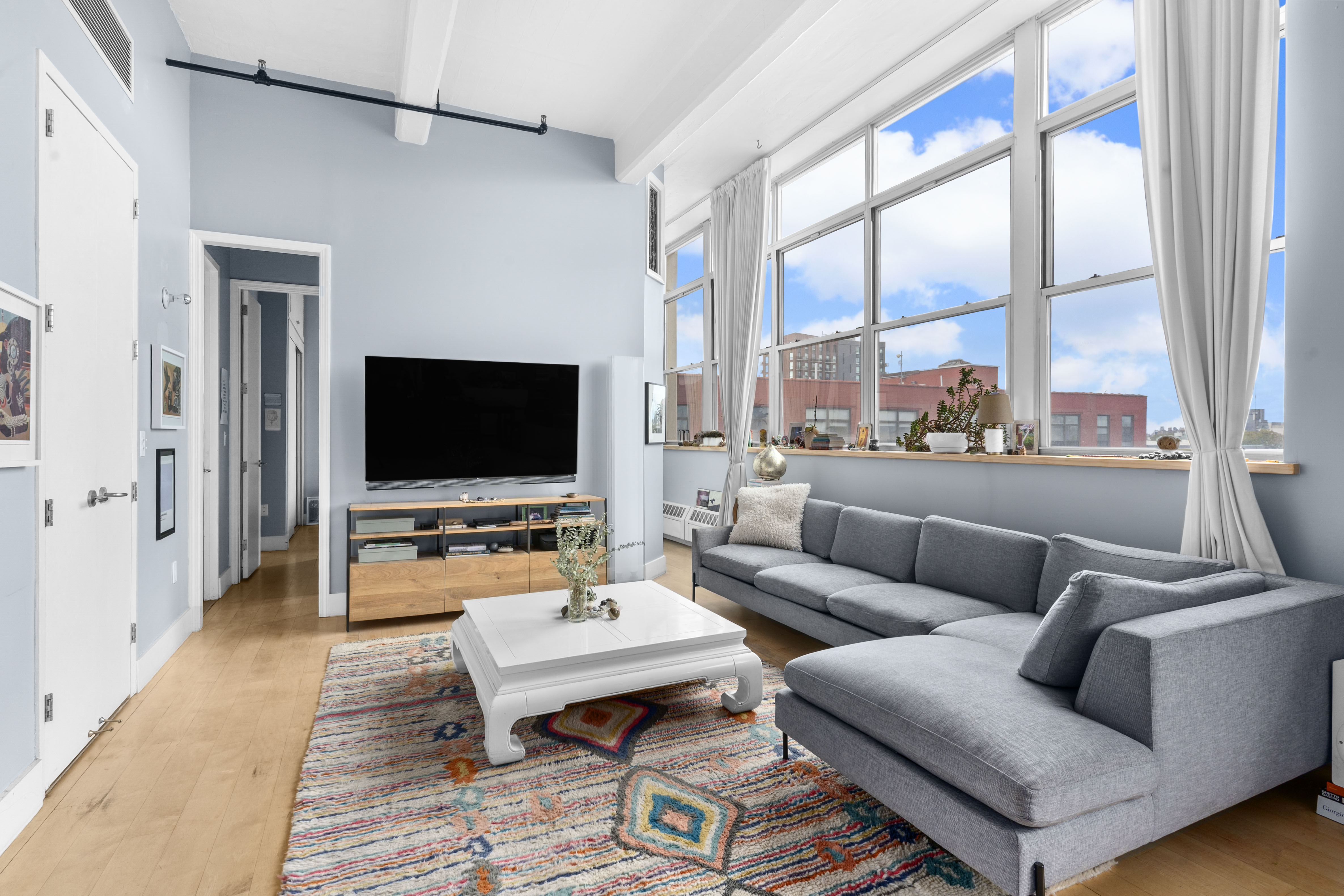 970 Kent Avenue, Unit 513 Brooklyn, NY 11205 - Photo 3 of 8 a living room with furniture a large window and a flat screen tv