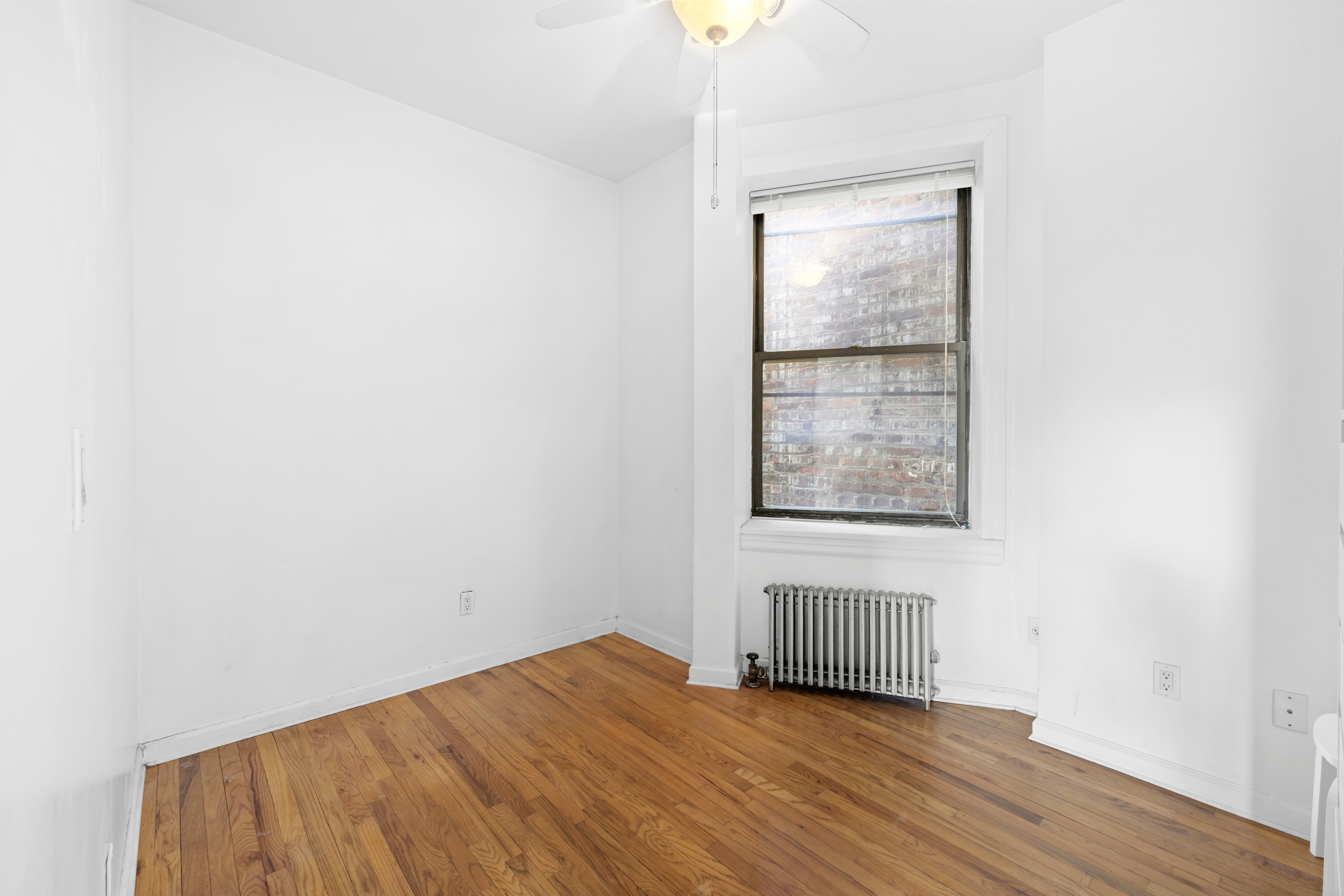 469 West 166th Street, Unit 2C Manhattan, NY 10032 - Photo 8 of 13 a view of an empty room with wooden floor and a window