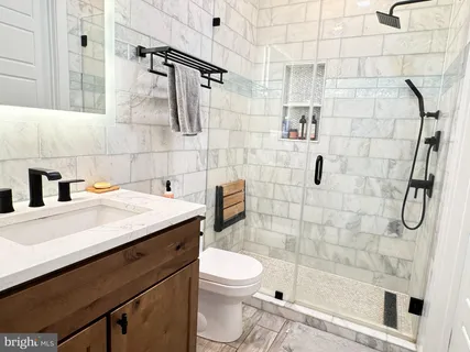 a bathroom with a granite countertop sink a toilet and shower