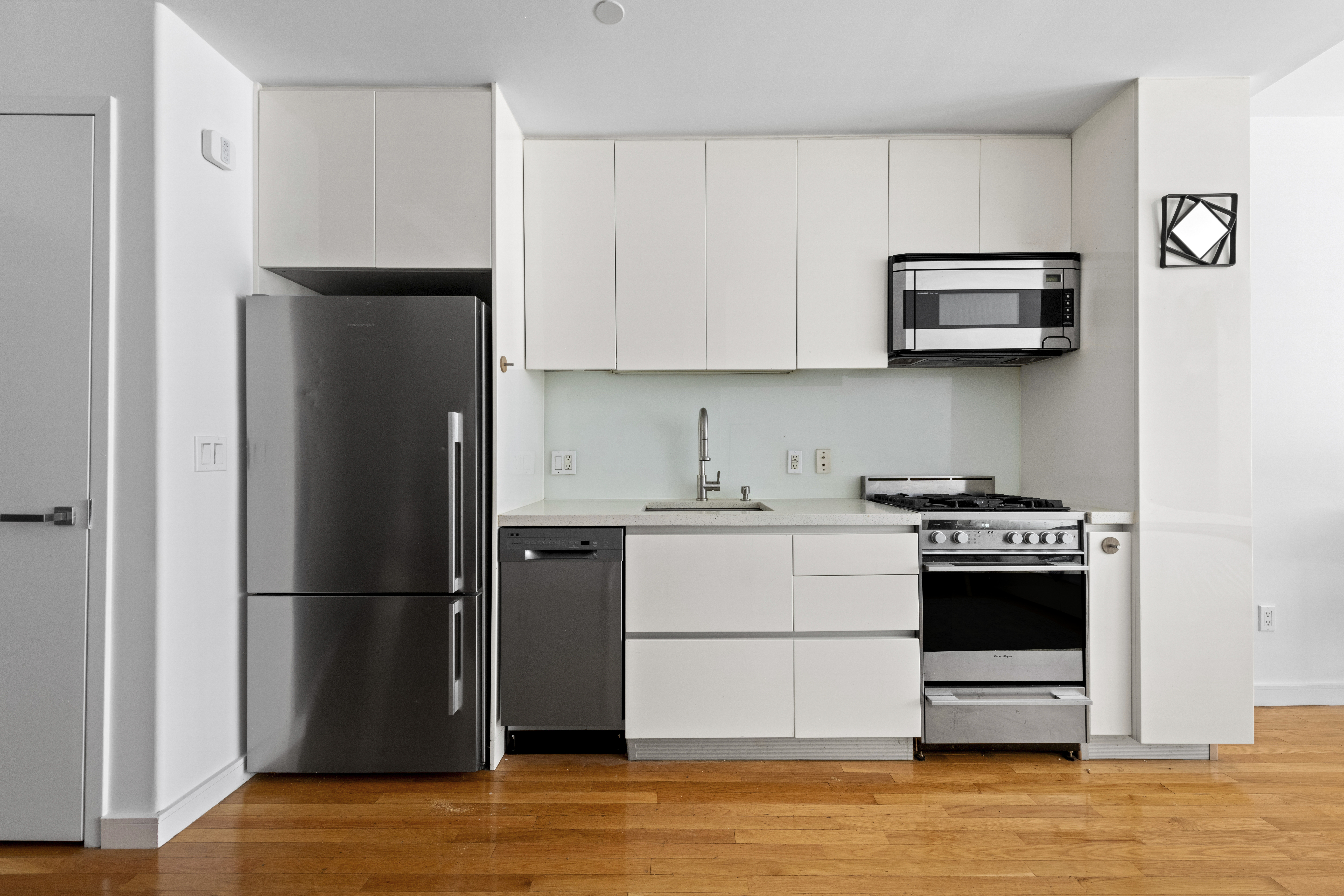 148 East 24th Street, Unit 3D Manhattan, NY 10010 - Photo 4 of 15 a kitchen with stainless steel appliances a refrigerator stove and microwave