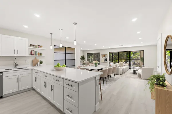 a view of a kitchen with kitchen island a large counter top space a sink stainless steel appliances and cabinets