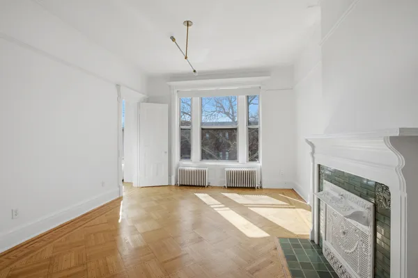 a view of an empty room with window and wooden floor