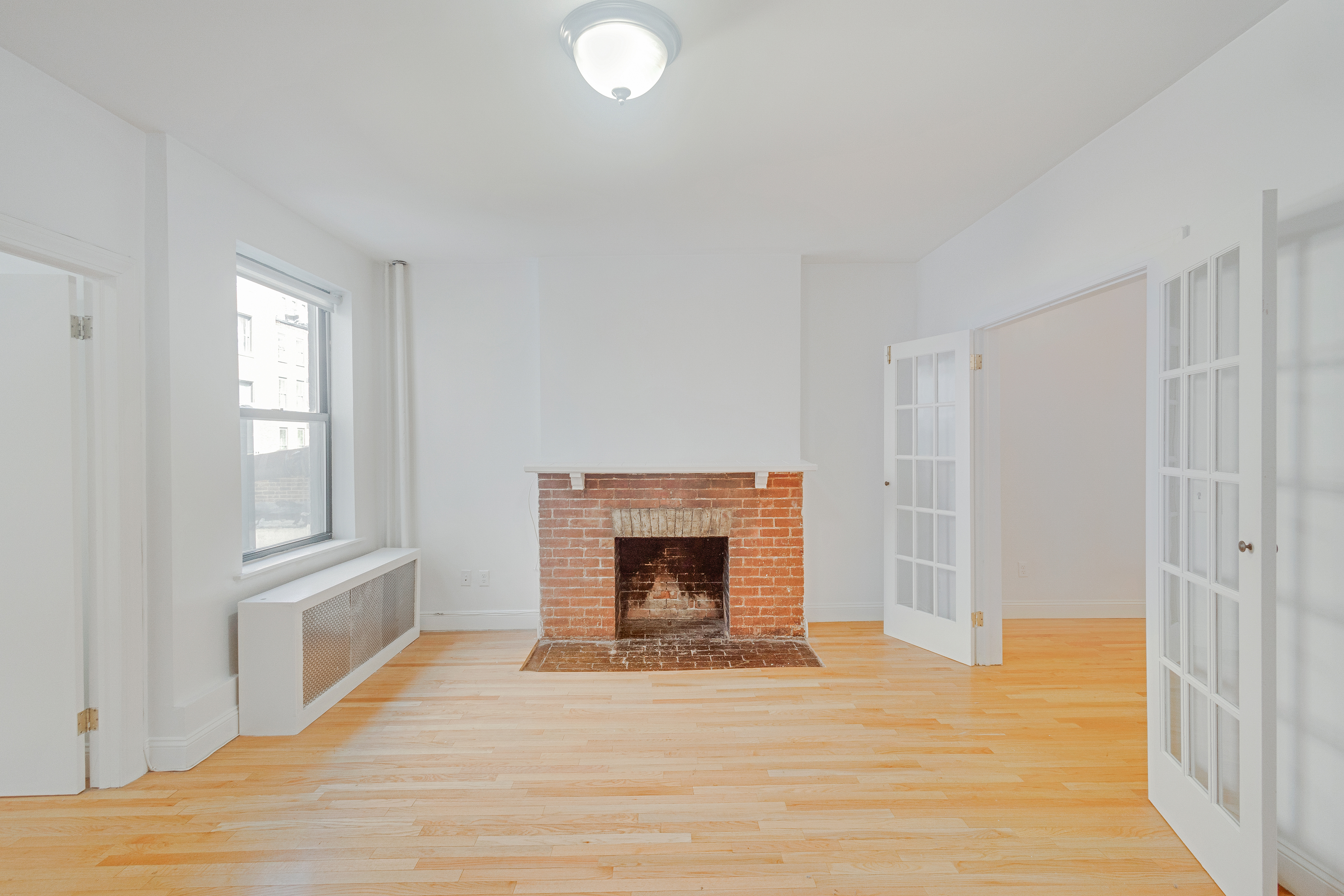 167 West 72nd Street Manhattan, NY 10023 - Photo 8 of 25 a view of an empty room with wooden floor fireplace and a window
